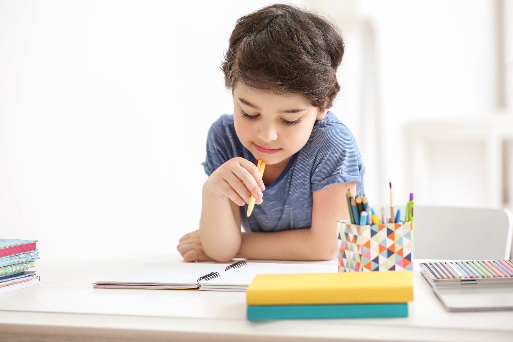 Pensive Boy Preparing to Write on a Notebook